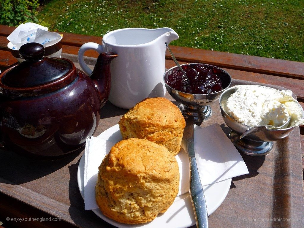 A classical Cream Tea: Two scones (here plain ones without raisins) and tons of clotted cream and jam in the little bowls. It is accompanied by a good tea and always with fresh milk.